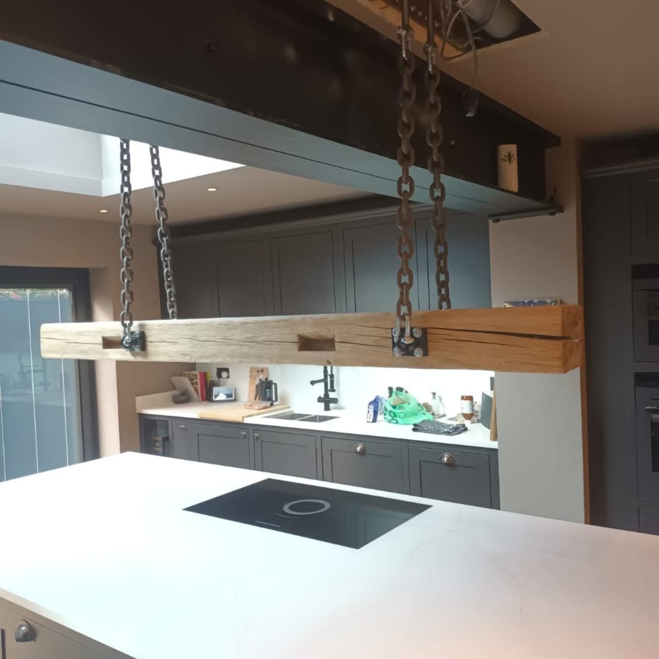 Reclaimed oak beam suspended on chains above a kitchen island